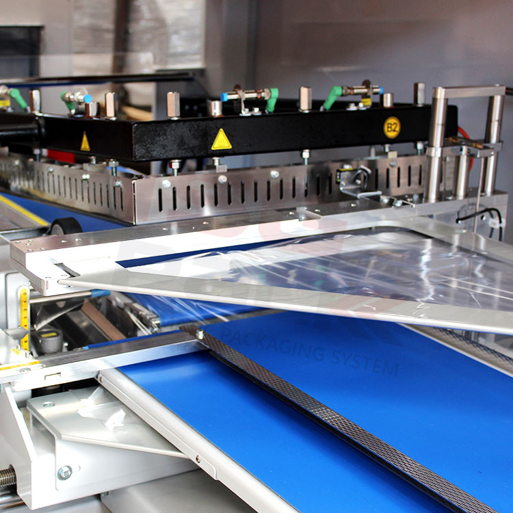Zbliżenie na mechanizm zgrzewarki kątowej do pakowania produktów w folię termokurczliwą.